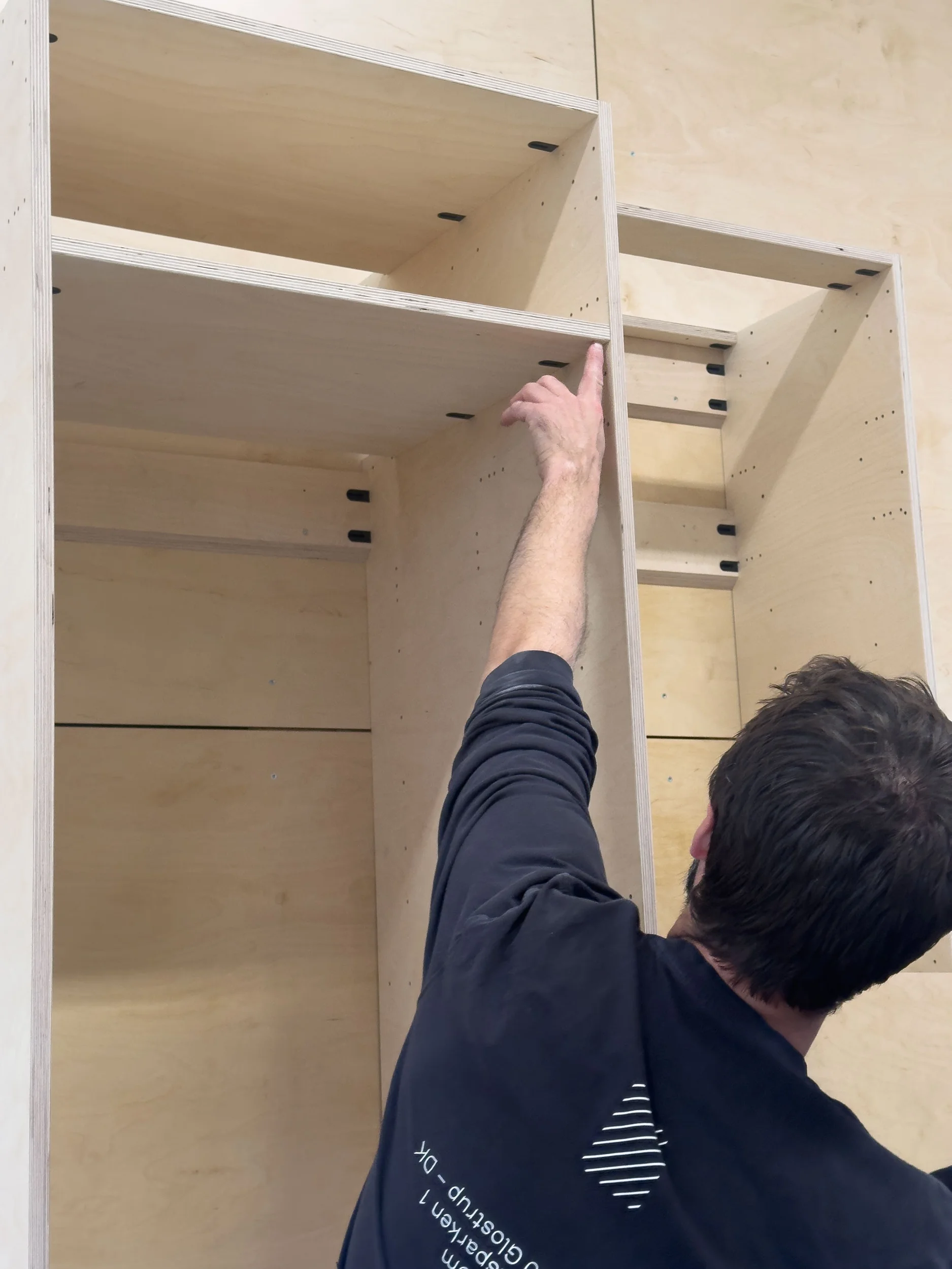 Close-up of a craftsperson installing custom birch plywood modular cabinetry units by Stykka.