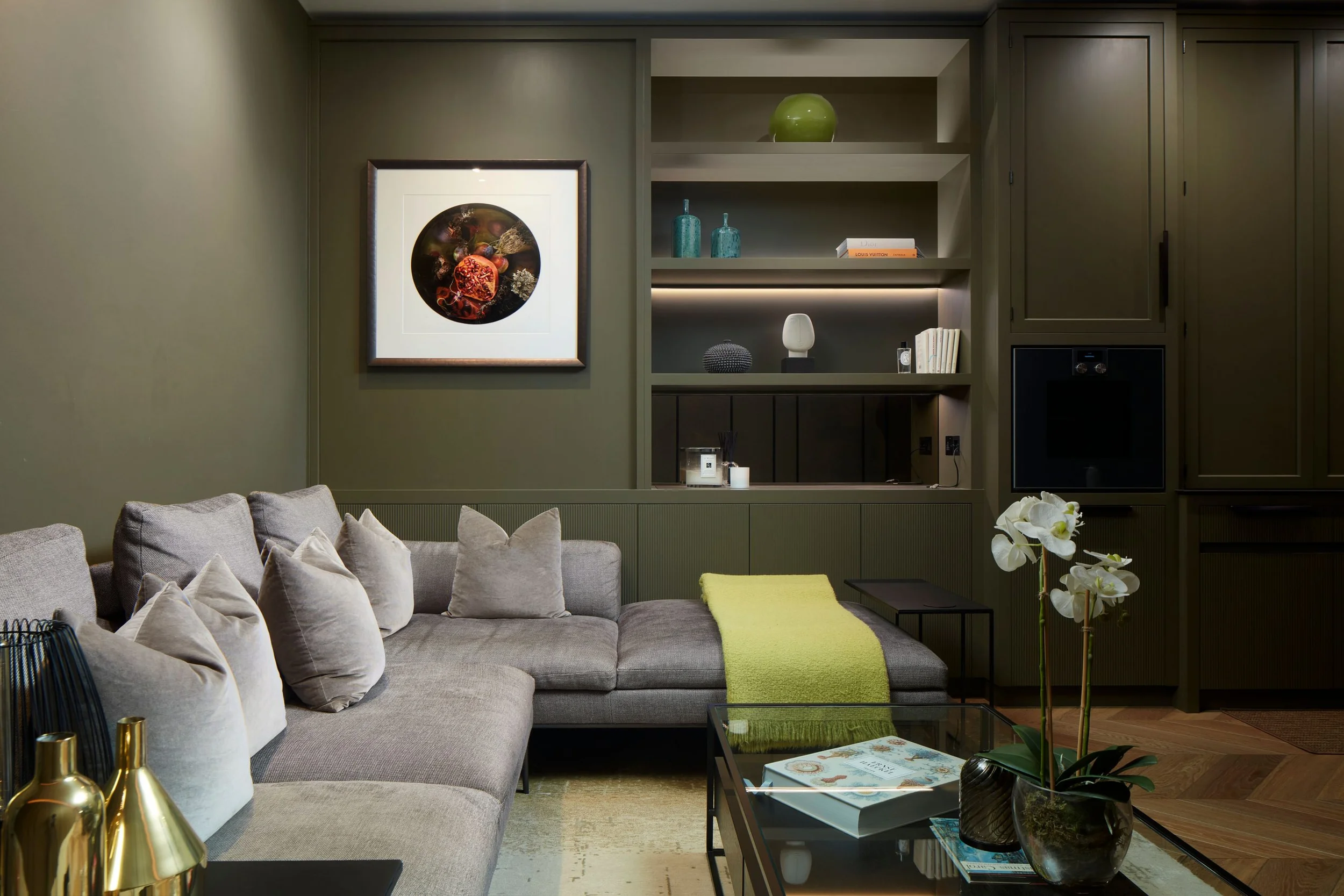Interior living space with olive green millwork and grey sectional sofa by Carden Cunietti.