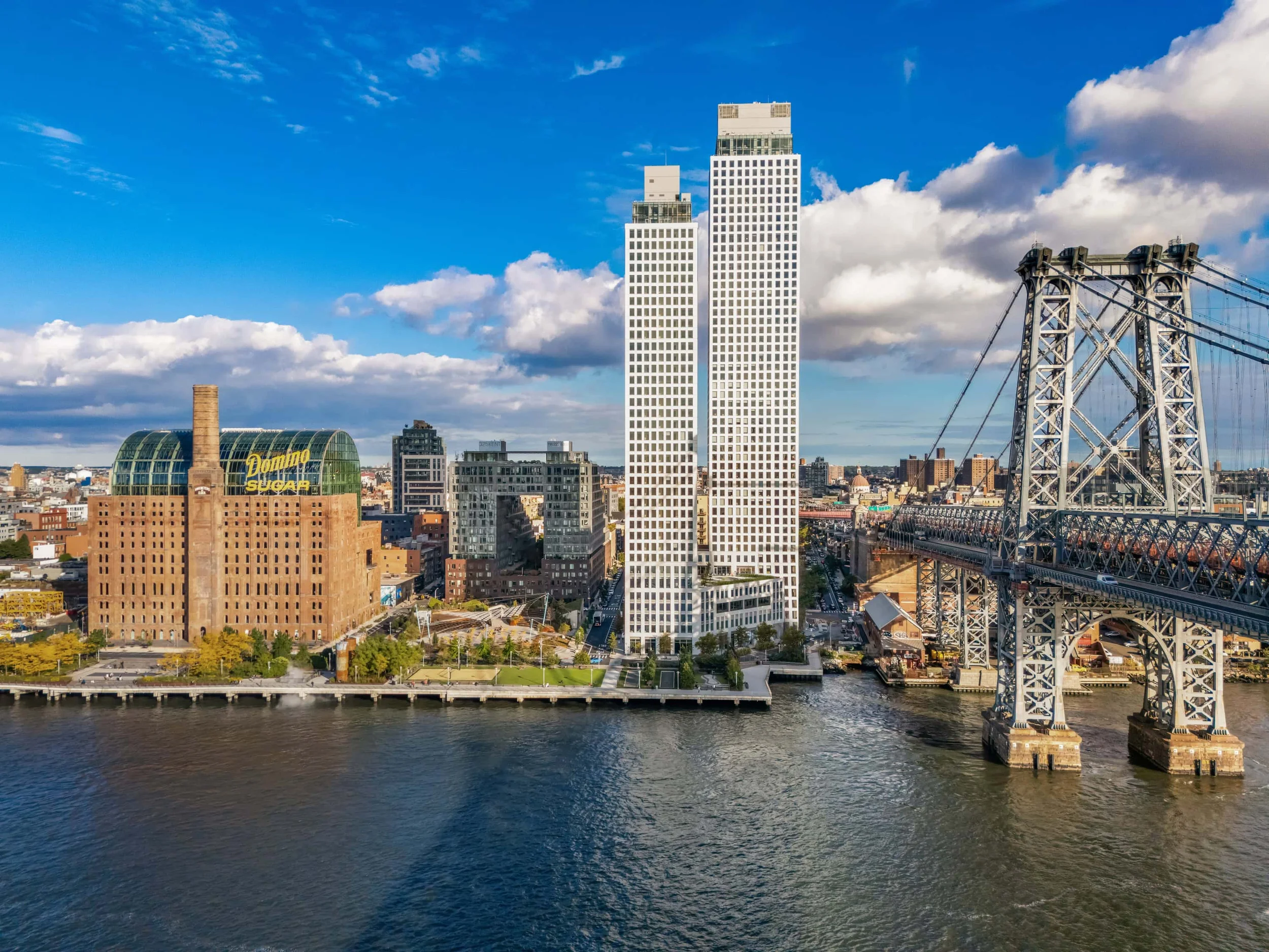 Aerial view of One Domino Square twin towers next to the historic Domino Sugar refinery and Williamsburg Bridge by Selldorf Architects.