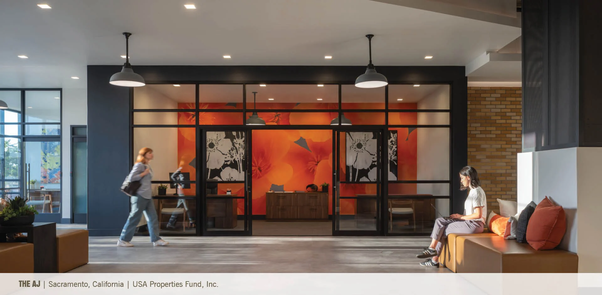 Interior lobby with black metal framed glass partitions and a bright orange floral accent wall by DAHLIN Architecture.