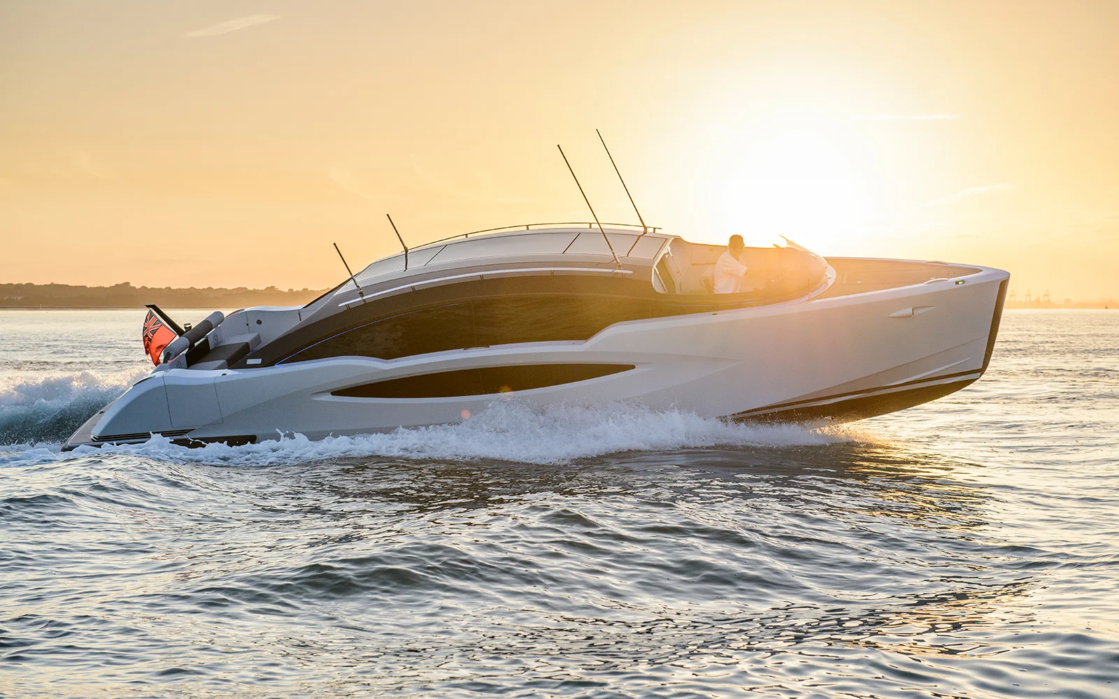 Sleek white motor yacht by H2 Yacht Design cutting through calm water at sunset.