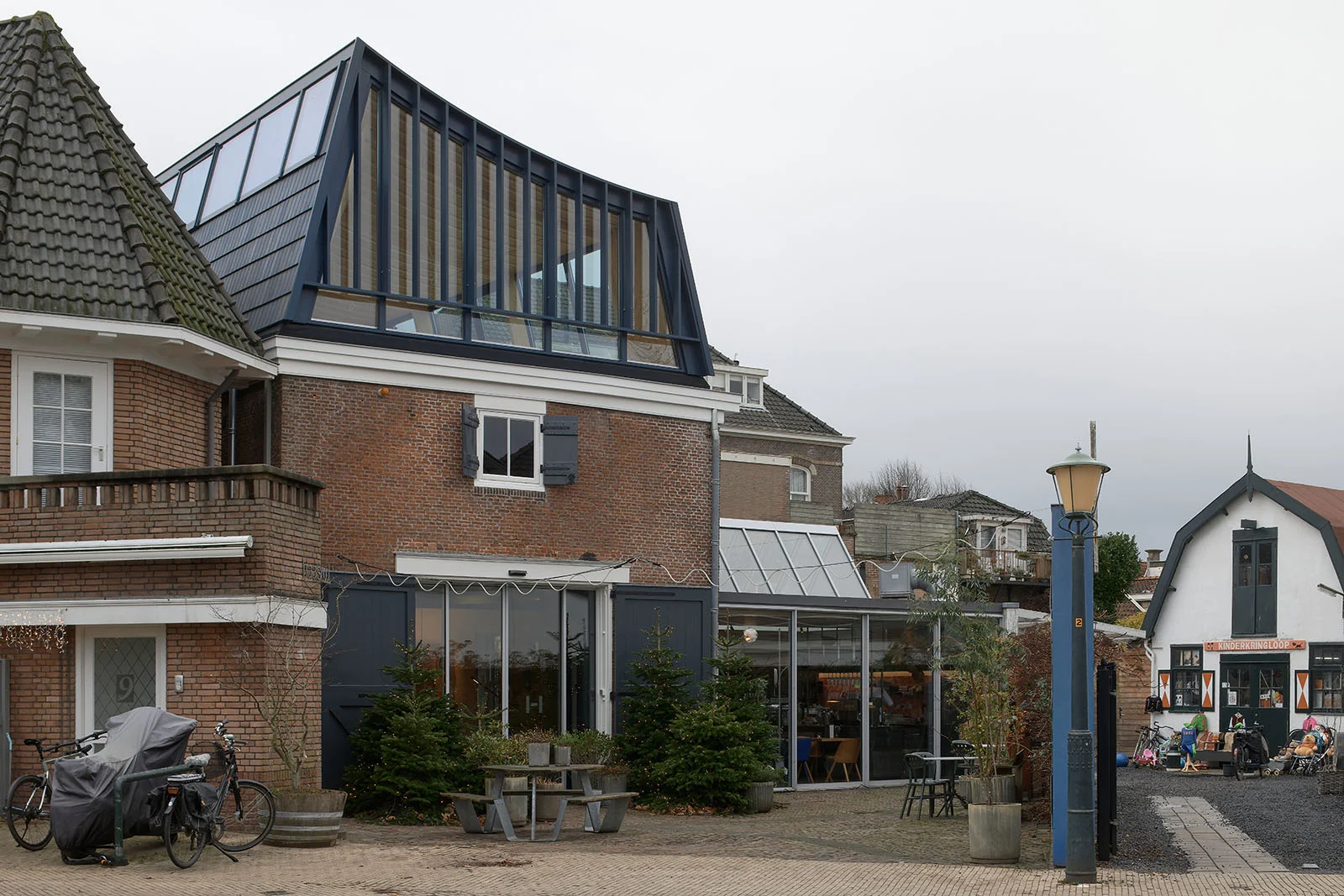 Exterior street view of a traditional brick building with a modern dark-framed zinc and glass mansard roof addition by Unknown Architects.