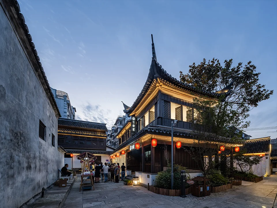 Evening street view of traditionally styled timber and stucco buildings with upturned eaves in Yuyao Yangming Ancient Town by Urban Fabric.