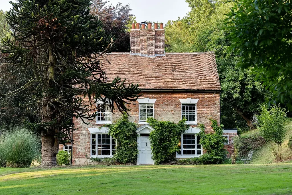 Exterior facade of a historic brick farmhouse with clay tile roof and central chimney stack by James Clague Architects.