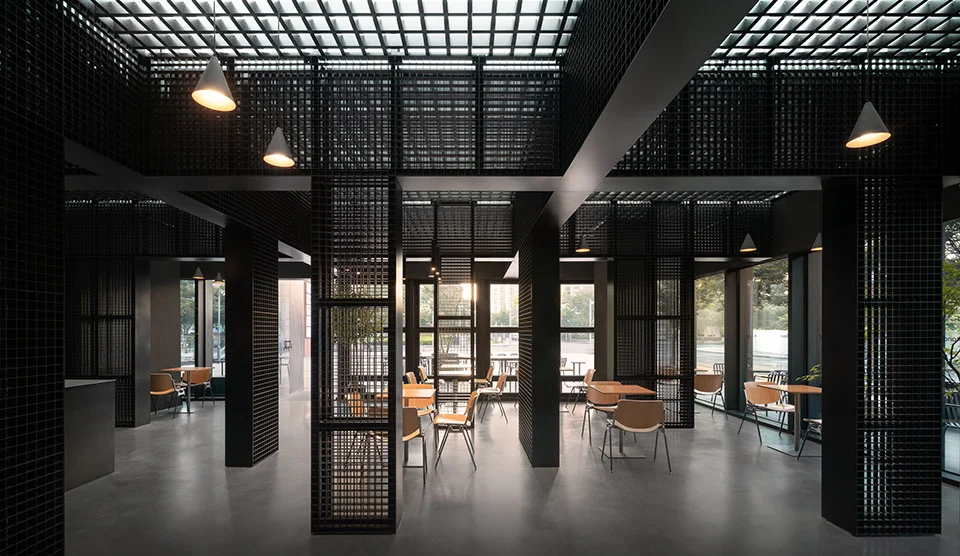 Interior of a cafe in Shanghai by Dazhou Architecture Design, featuring dark metal mesh screens, gridded ceiling coffers, and minimalist seating.