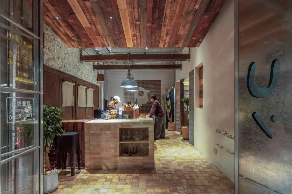 Interior perspective of JIU Restaurant by Muji Architectural Design Studio, showing textured tile floor, reclaimed wood ceiling, and central service counter.