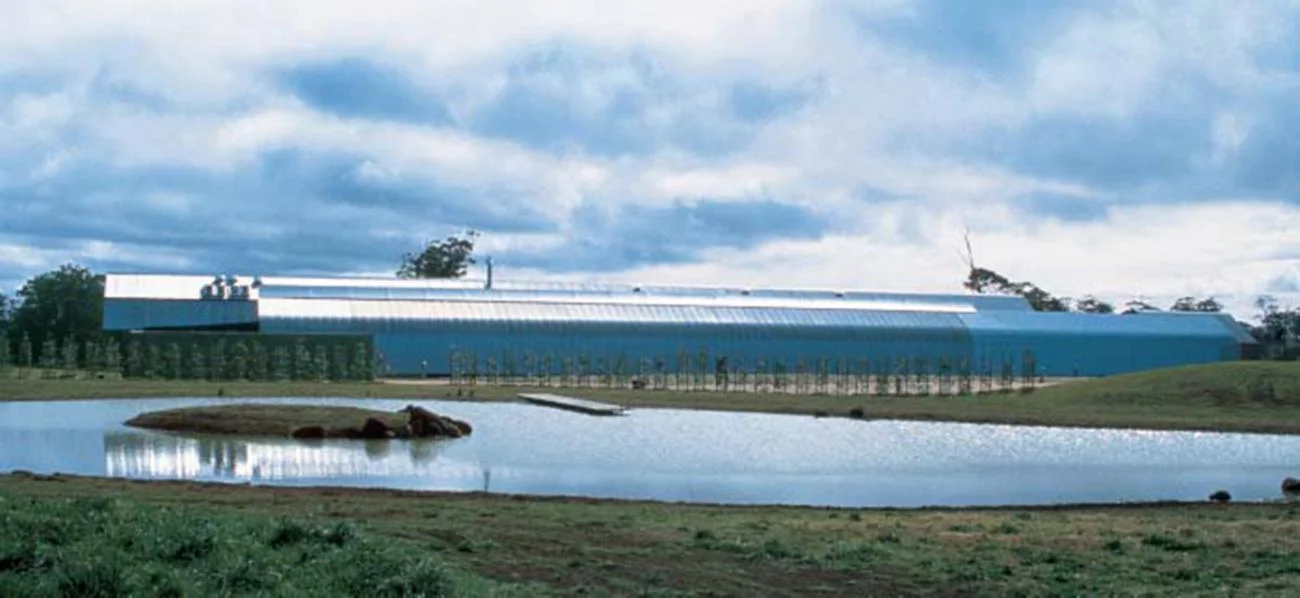 Bowral House by Glenn Murcutt, showing a long corrugated metal building behind a pond in New South Wales.