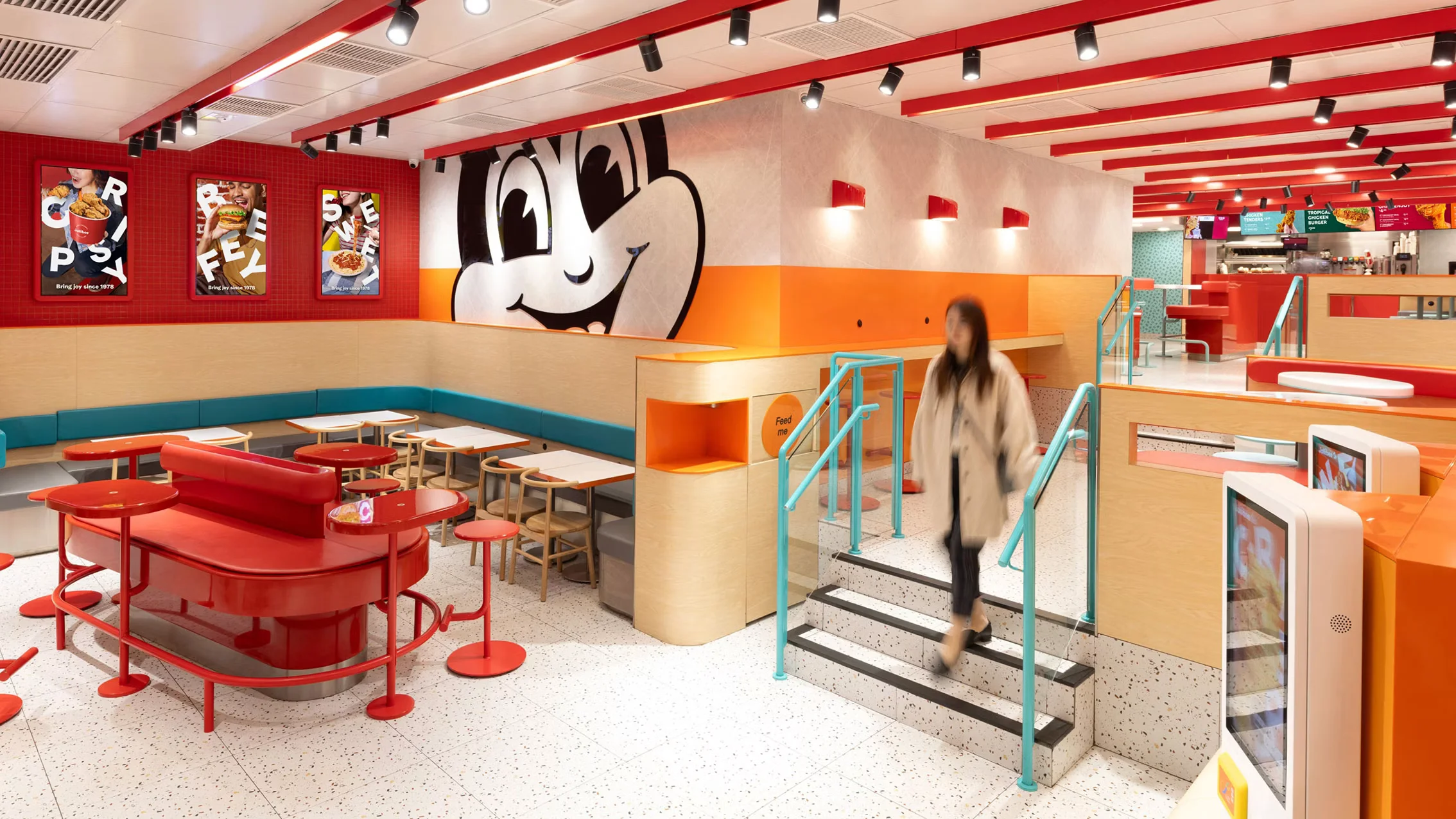 Bright, colorful fast-food interior designed by Shed with red booths, terrazzo floor, and a large cartoon graphic wall.