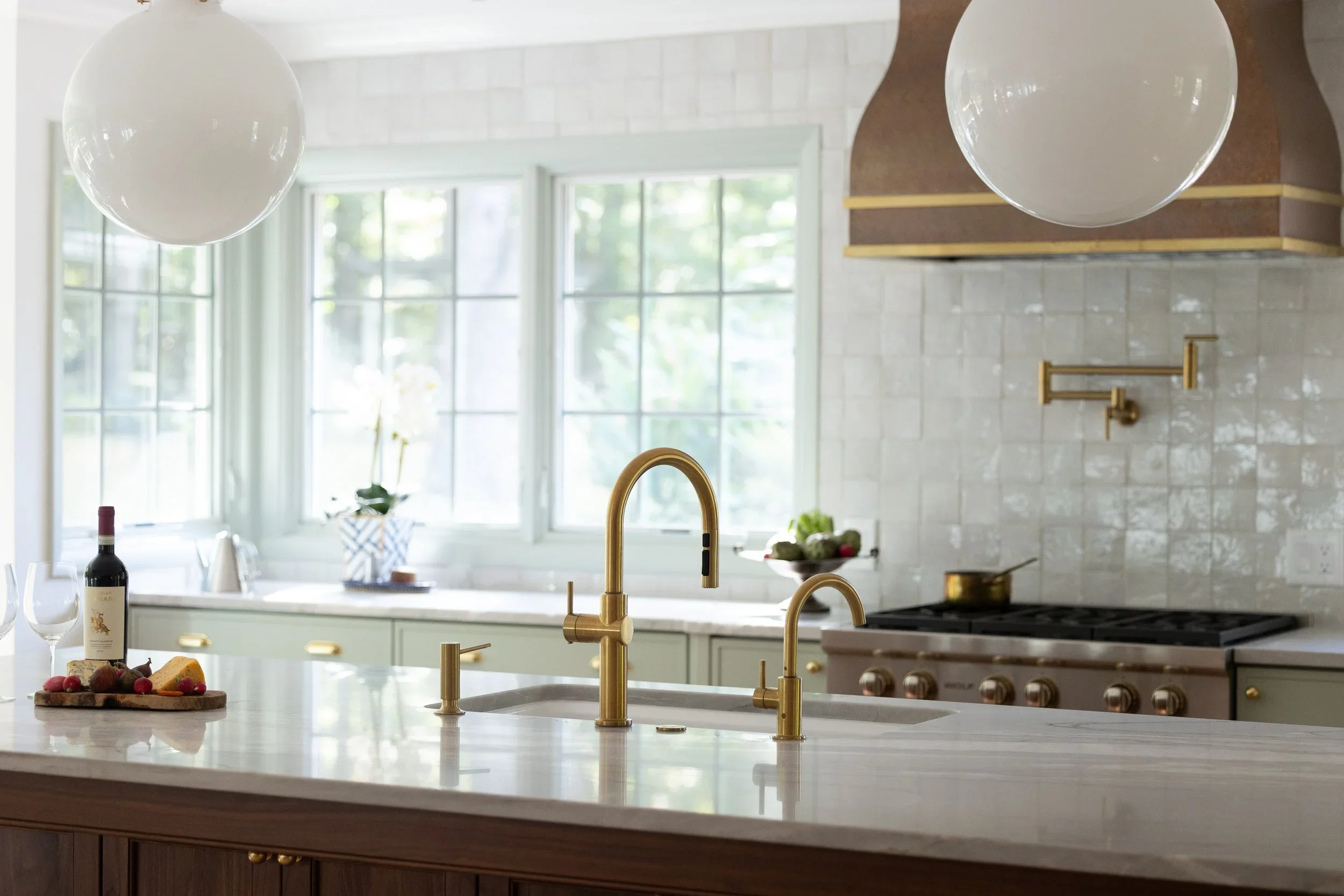 Kitchen interior by Will Johnson Building Company featuring marble island, brass fixtures, and zellige tile backsplash.