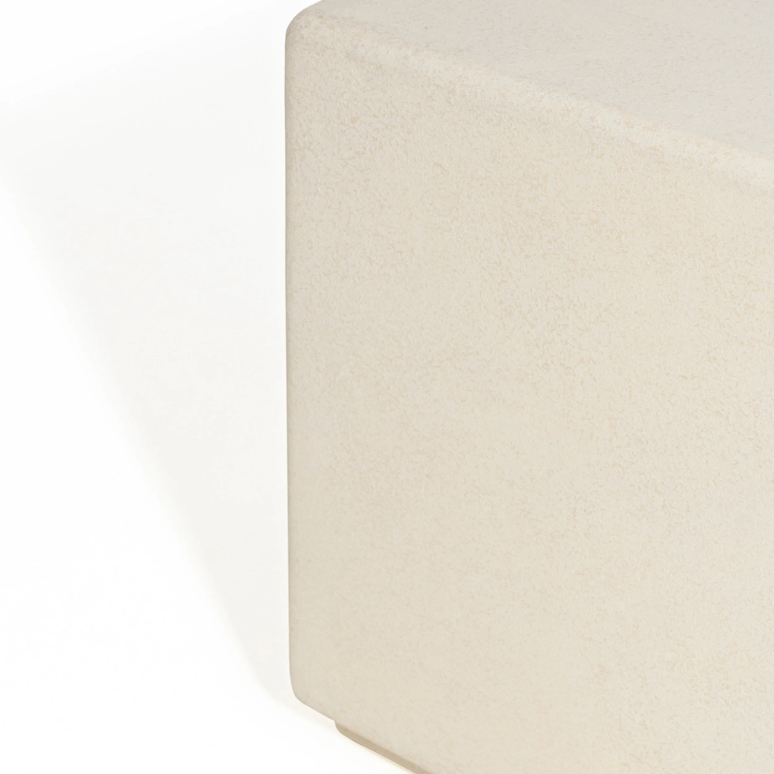 Close-up product or furniture detail of a monolithic beige textured stone block with rounded edges by Van Thiel & Co.