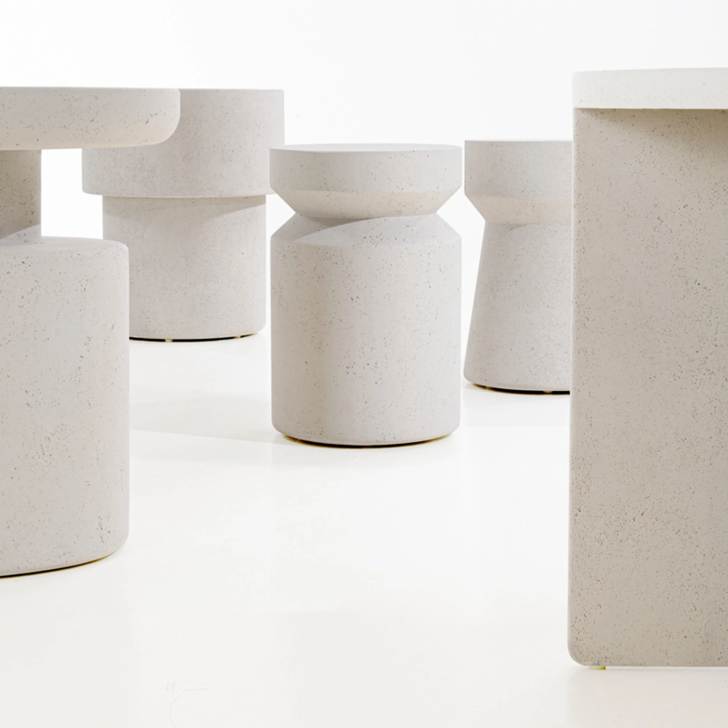 Collection of minimalist cast stone tables and stools with stepped cylindrical profiles by Van Thiel & Co.