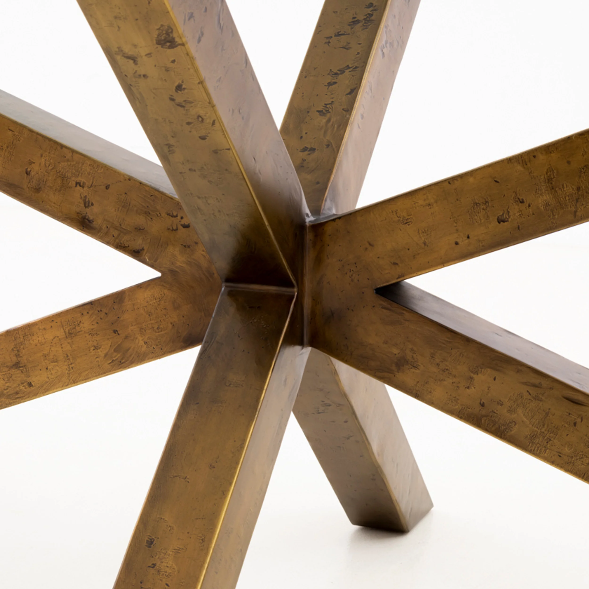 Close-up studio shot of a metal furniture base with intersecting angled bronze-finished bars by Van Thiel & Co.