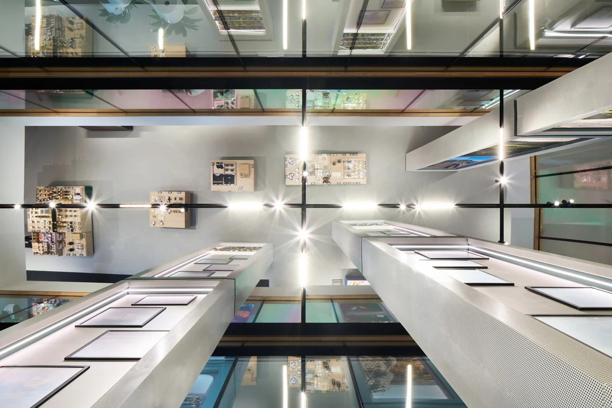 Upward perspective of a multi-story atrium interior with vertical perforated piers and glass ceiling elements by Ippolito Fleitz Group.