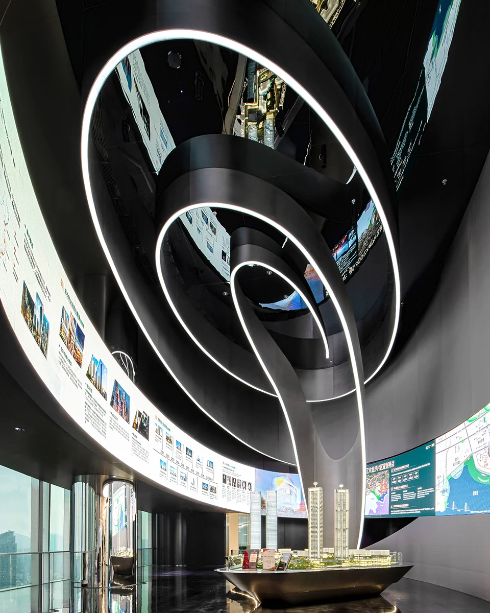 Curved digital display walls and a swirling illuminated ceiling sculpture by QUAD Studio.