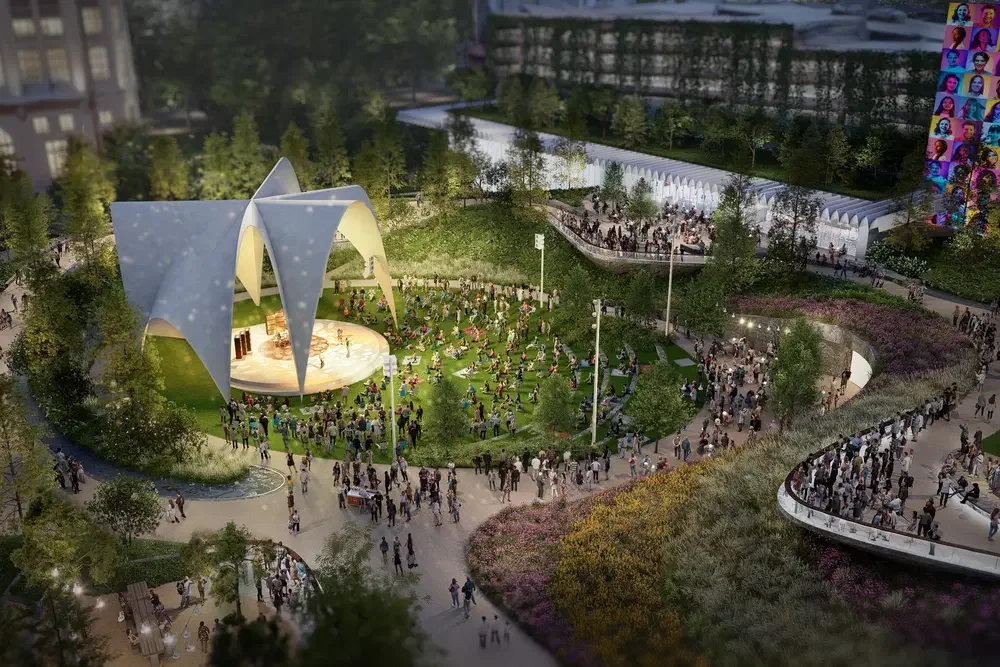 Aerial night view of an urban park by Field Operations featuring a glowing sculptural amphitheater canopy, terraced landscape, and crowds.