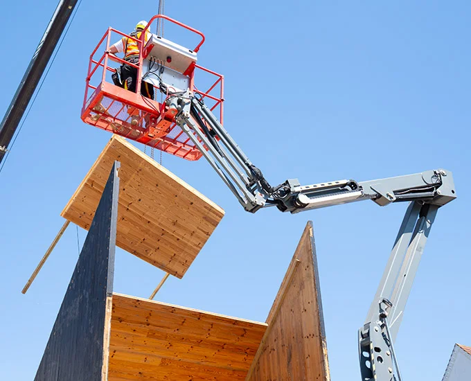 Construction crane lifting a timber panel onto a pavilion structure by Whitby Wood.