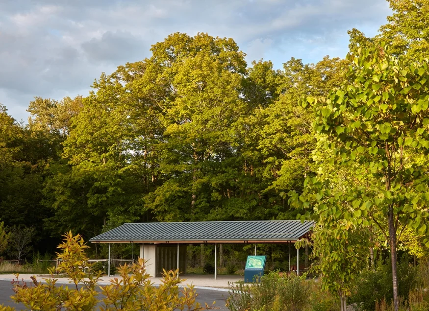 Single-story open-air park pavilion with metal gable roof and slim steel columns by Heneghan Peng Architects.