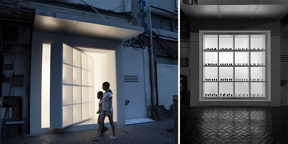 Night view of FLIPPOP Art Space facade in Shanghai featuring a massive pivoting gridded glass door opening to the street.
