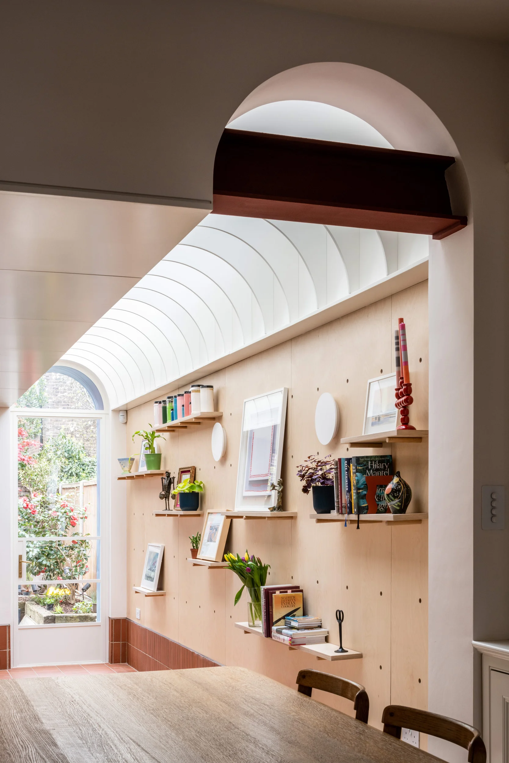 Interior dining space with a barrel-vaulted skylight and plywood pegboard wall by Bradley Van Der Straeten Architects.