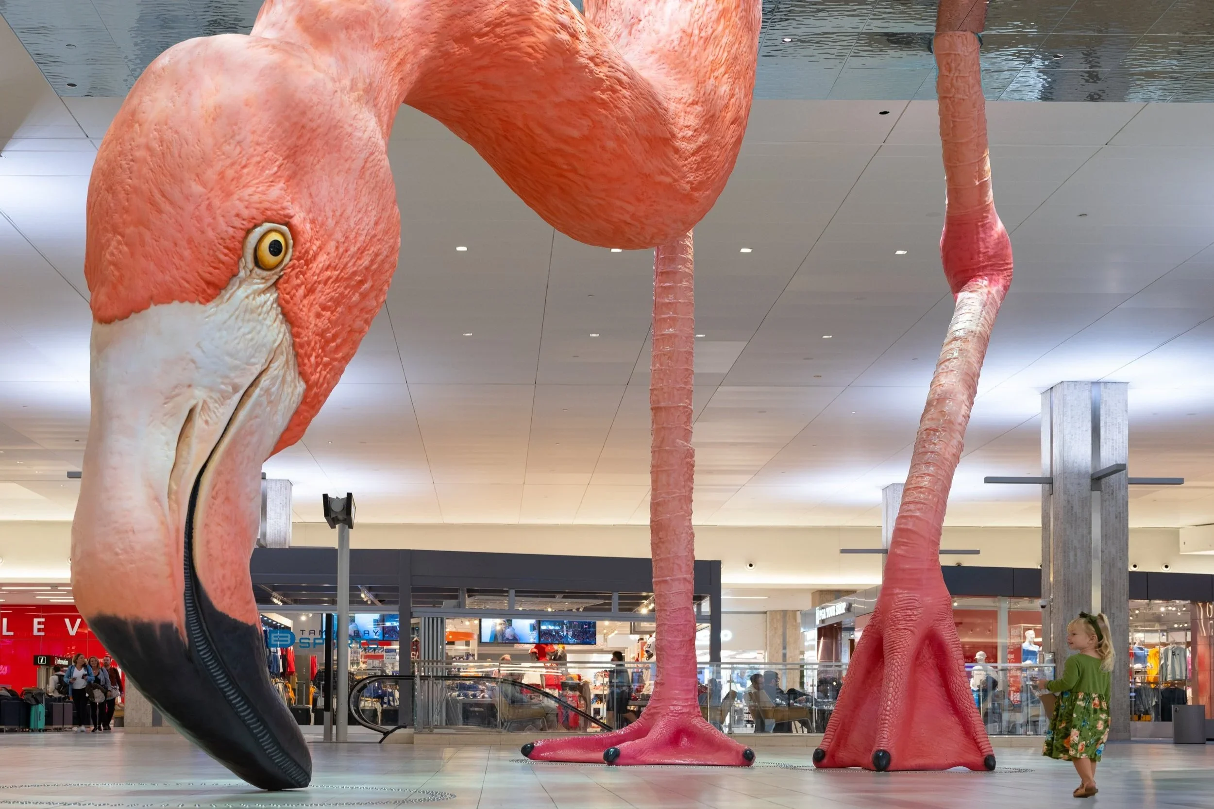 Oversized pink flamingo sculpture by Mazzotta Studio inside a public airport terminal or concourse.