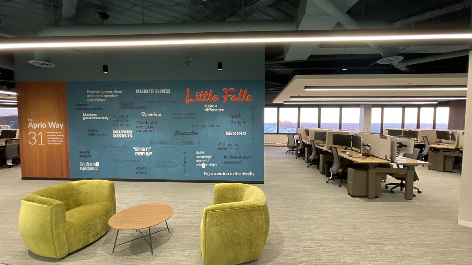 Open-plan corporate office interior with chartreuse lounge chairs and branded feature walls by Jarmel Kizel Architects.