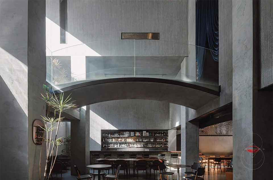 Double-height interior space featuring a curved glass bridge spanning across the central volume by XING DESIGN.