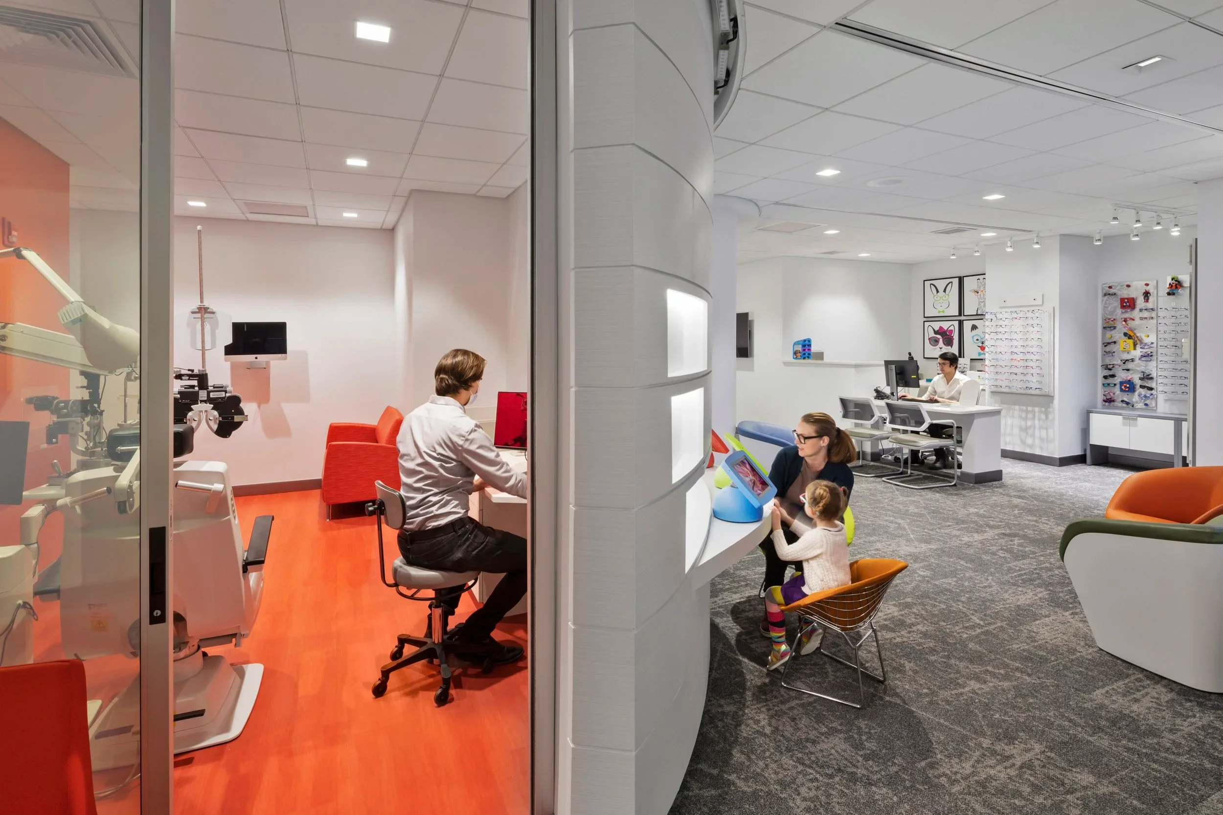 Interior view of an eye care clinic with a curved white partition wall and separate examination rooms by NK Architects.