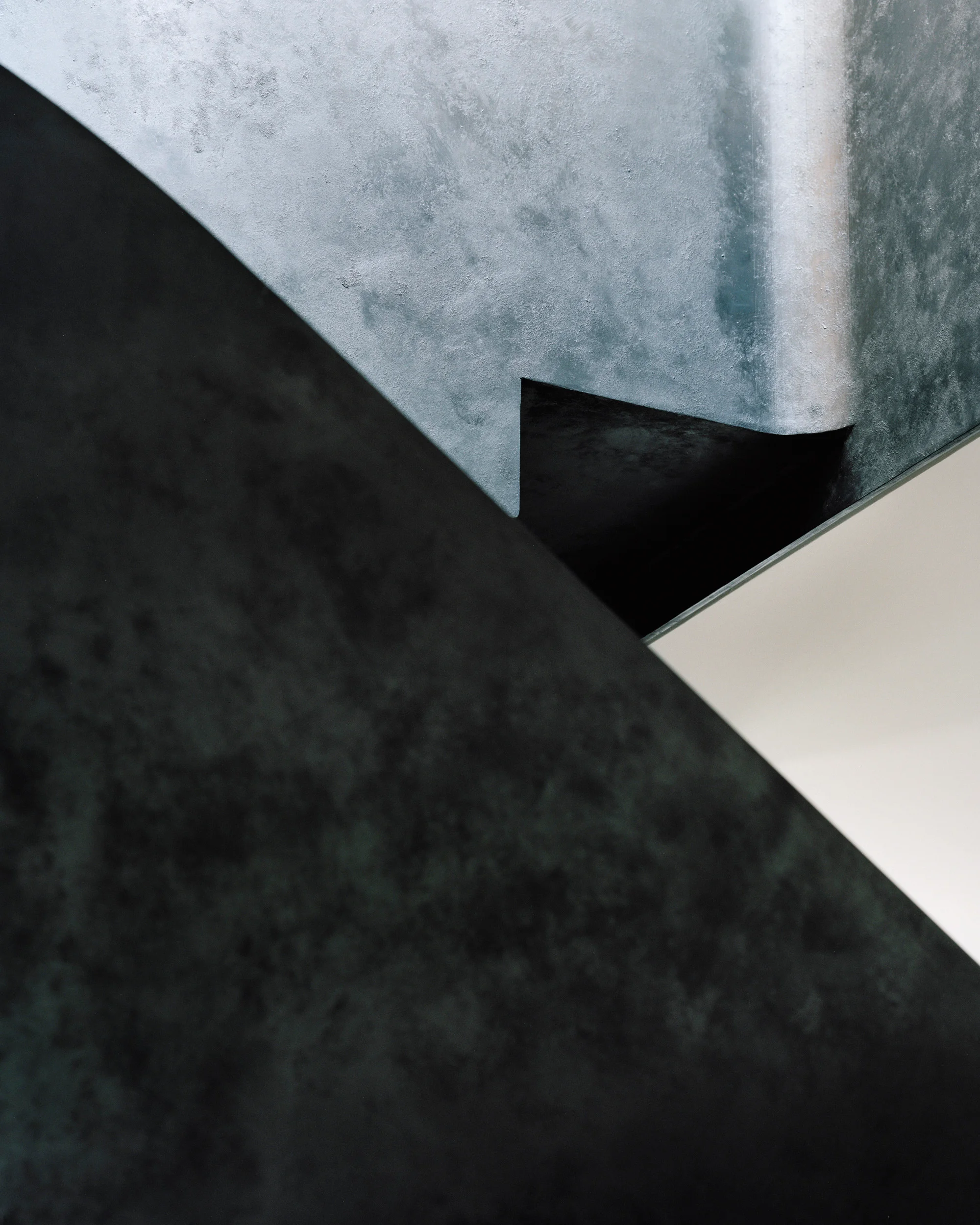 Abstract architectural detail by Tasou Associates showing angular intersecting planes of textured metal and dark surfaces.
