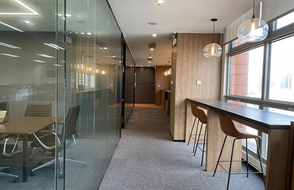 Interior office corridor by MG2 featuring a glass-walled conference room on the left and a wood-clad window bar on the right.