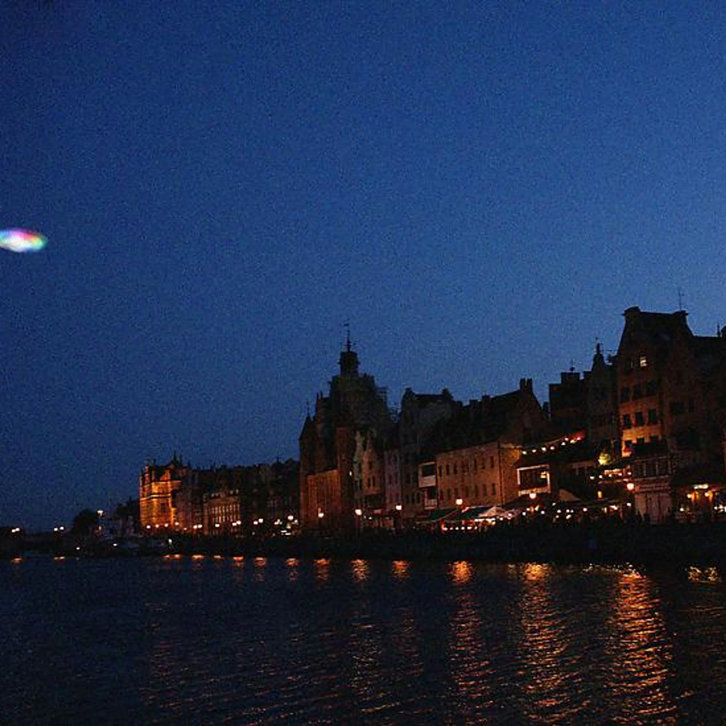 Night view of historic waterfront facades illuminated along the river edge by Cinimod Studio.