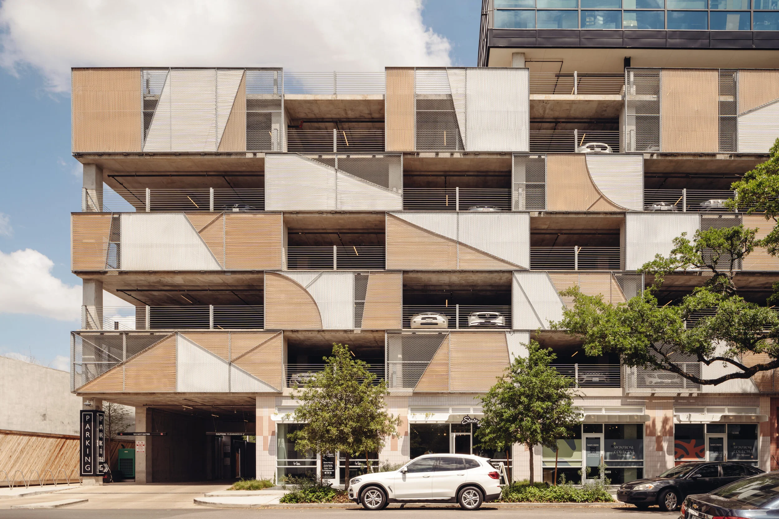 Multi-level parking garage with geometric metal mesh and wood slat facade panels by Michael Hsu Office of Architecture.