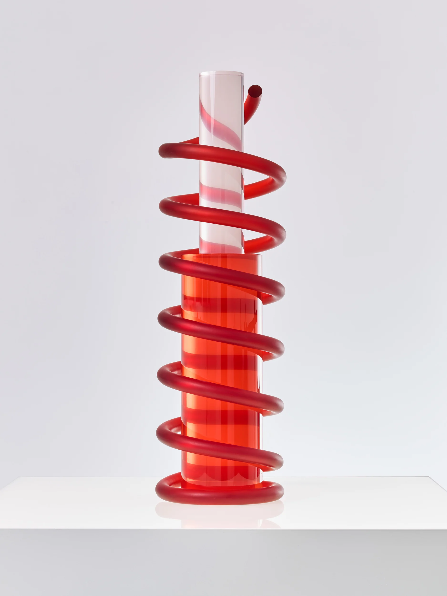 Physical architectural model of a vertical cylinder wrapped in a red glass spiral helix.