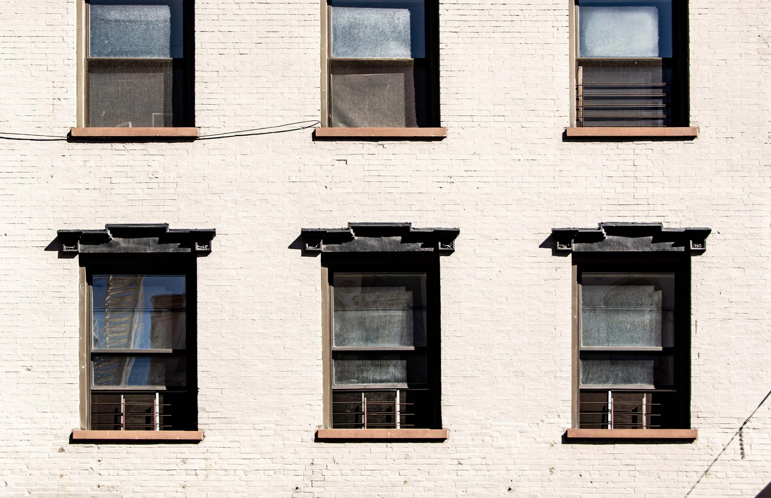 Exterior facade of 2 Bond Street showing painted white brick wall and regularly spaced double-hung windows with dark lintels by Kamen Tall Architects.