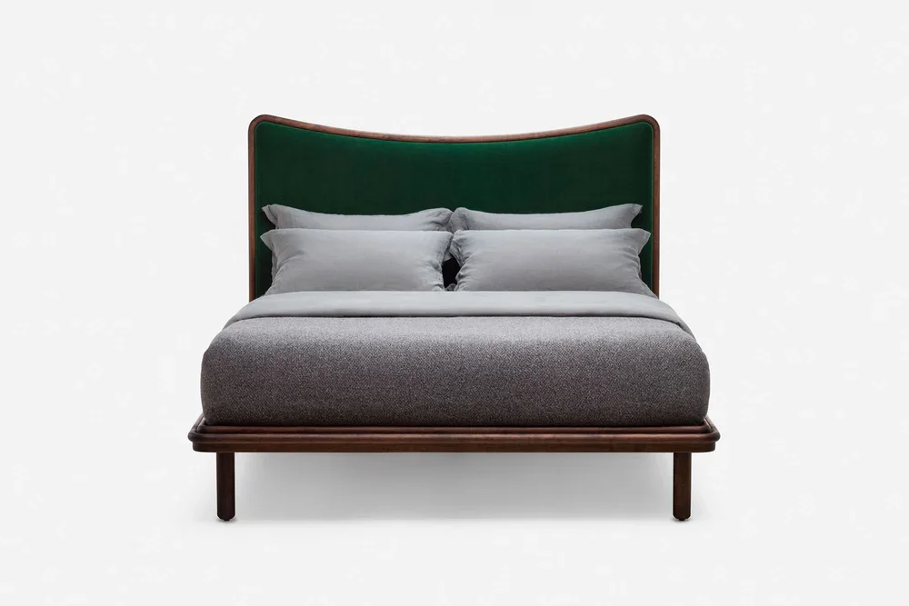 Front view of a modern wooden bed frame with a curved green velvet headboard and gray upholstery.