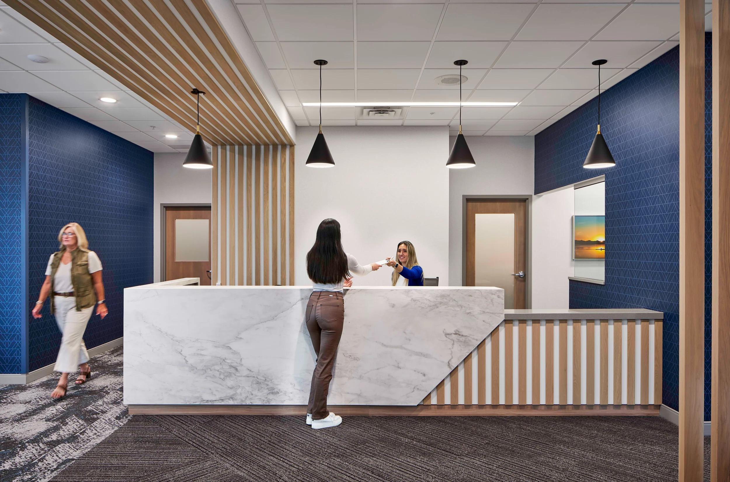 A corporate reception desk with marble cladding and vertical wood slats, designed by Mohagen Hansen Architectural Group.