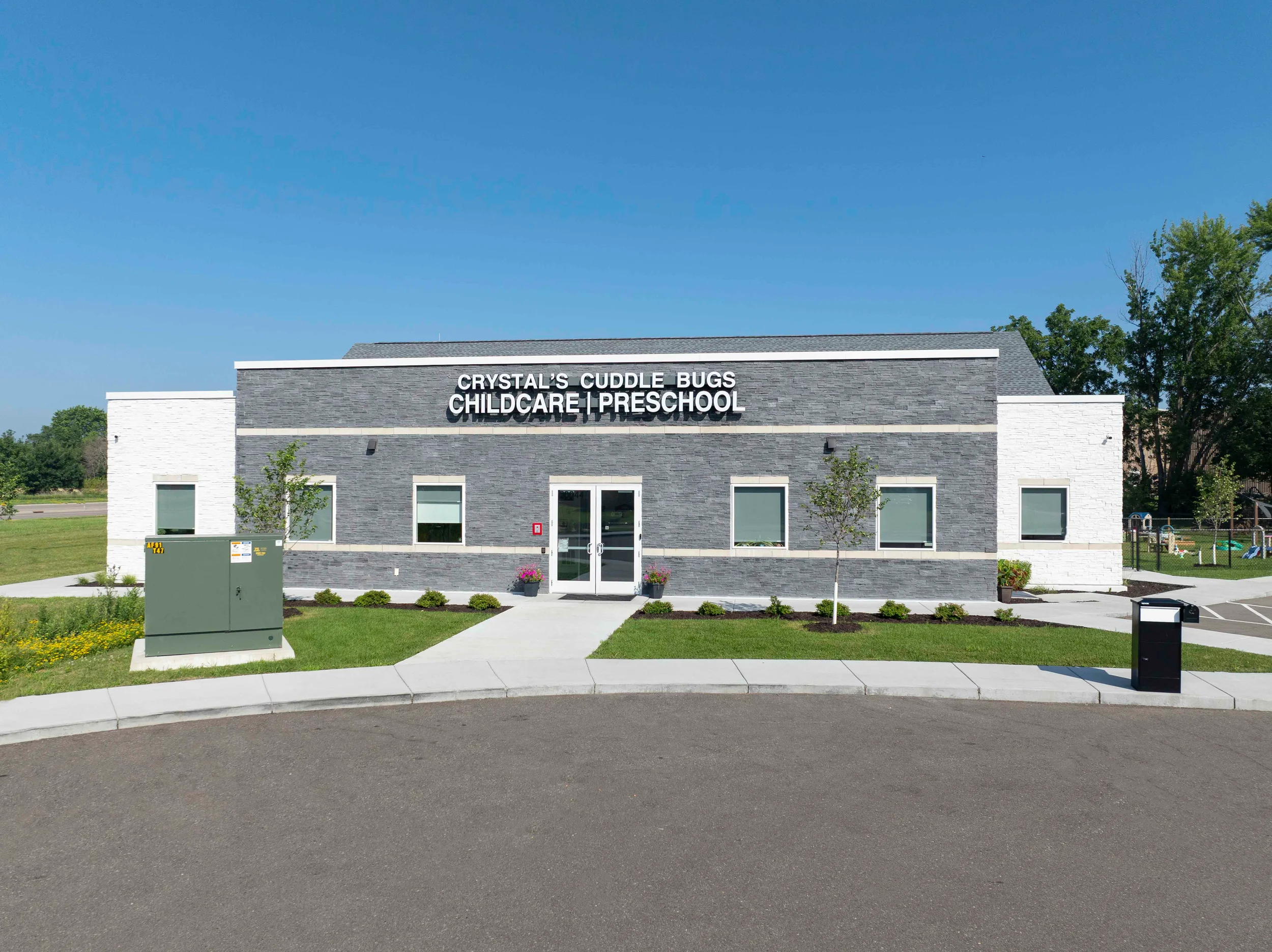 Single-story commercial building facade with stacked stone veneer and white side volumes by Mohagen Hansen Architectural Group.