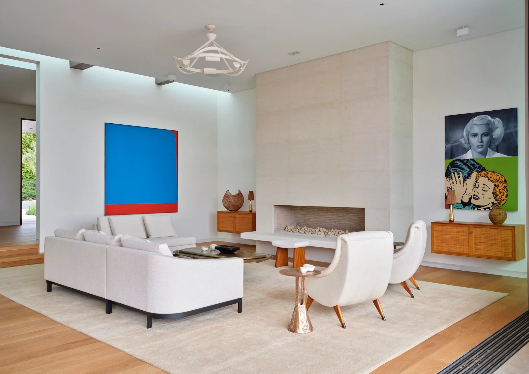 Spacious modern living room with white sectional sofa, limestone fireplace, and abstract art by Studio William Hefner.