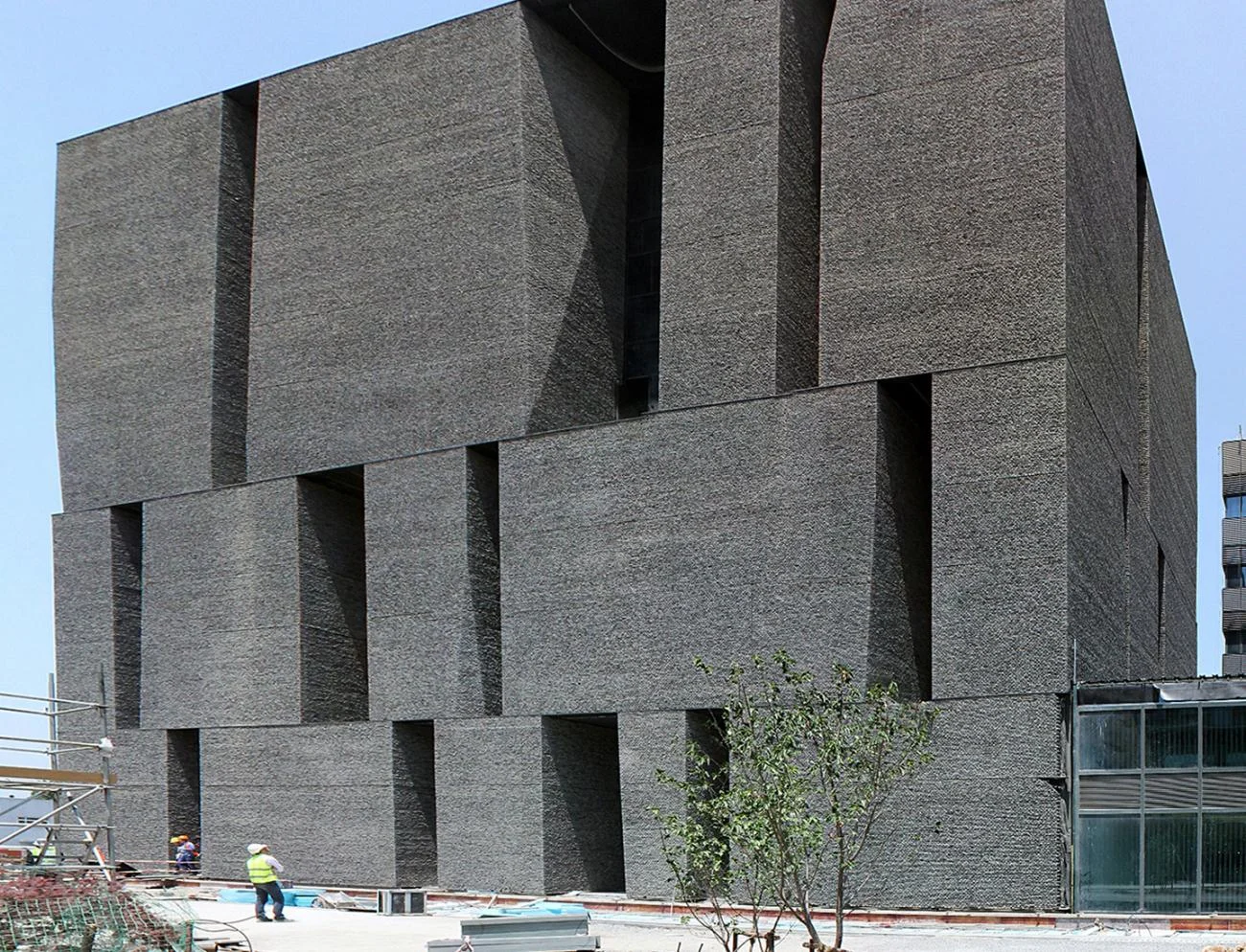 Textured concrete facade of the Novartis Office Building in Shanghai by Alejandro Aravena, featuring deep vertical slots.