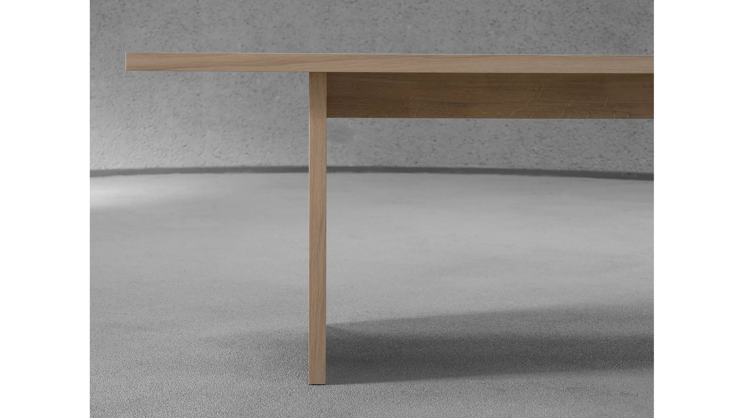 Close-up detail of a minimalist wooden table corner with slim square leg by Julius Taminiau Architects.