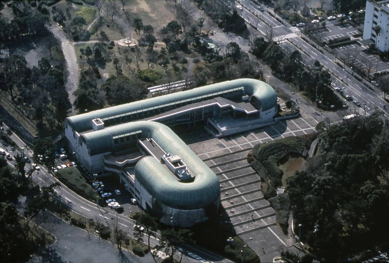 Aerial view of the Kitakyushu Central Library by Arata Isozaki, showing its curved, copper-vaulted roofs and plaza.