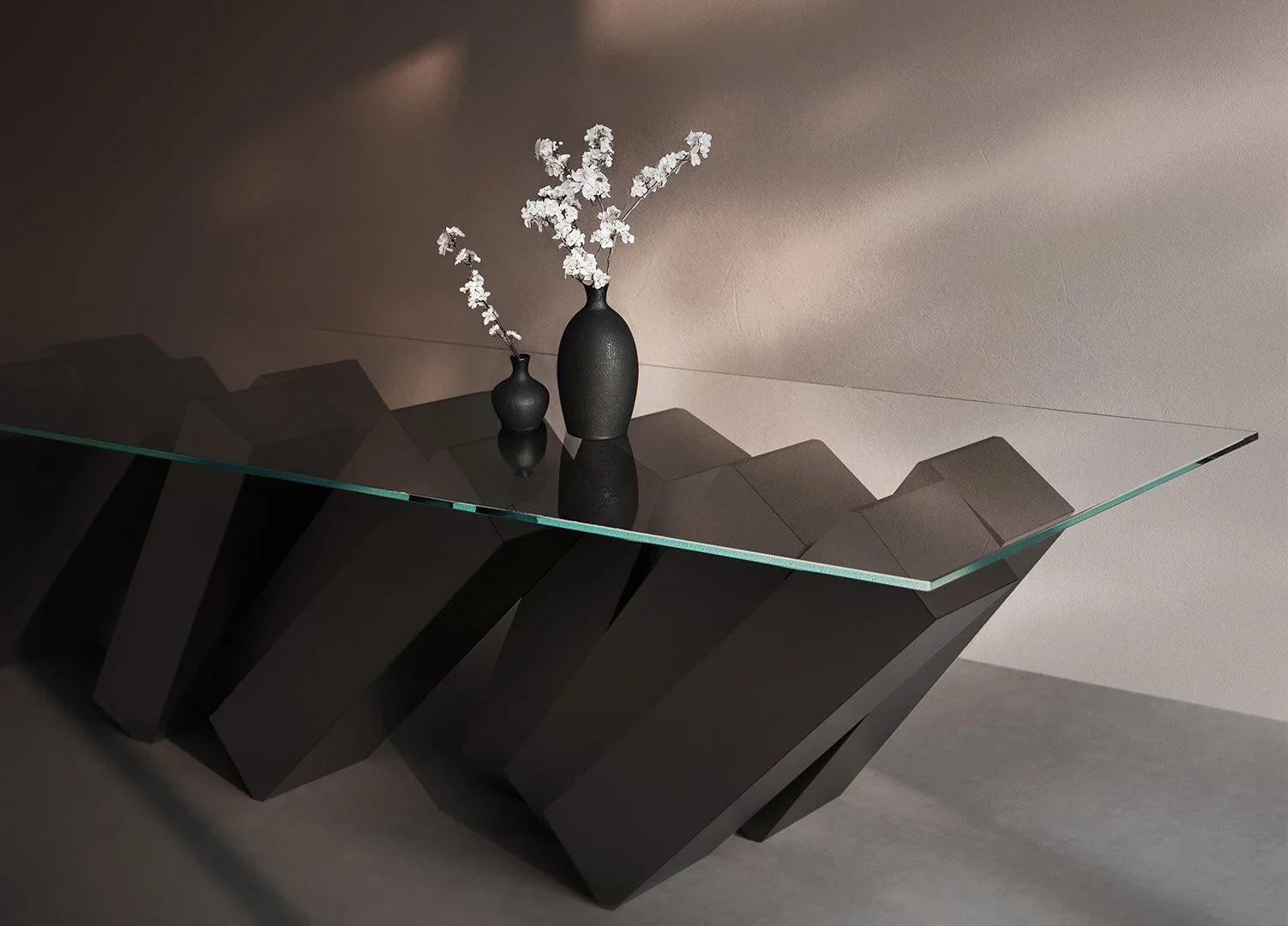 Monumental luxury dining table with faceted dark geometric bases and a clear glass top by Duffy London.