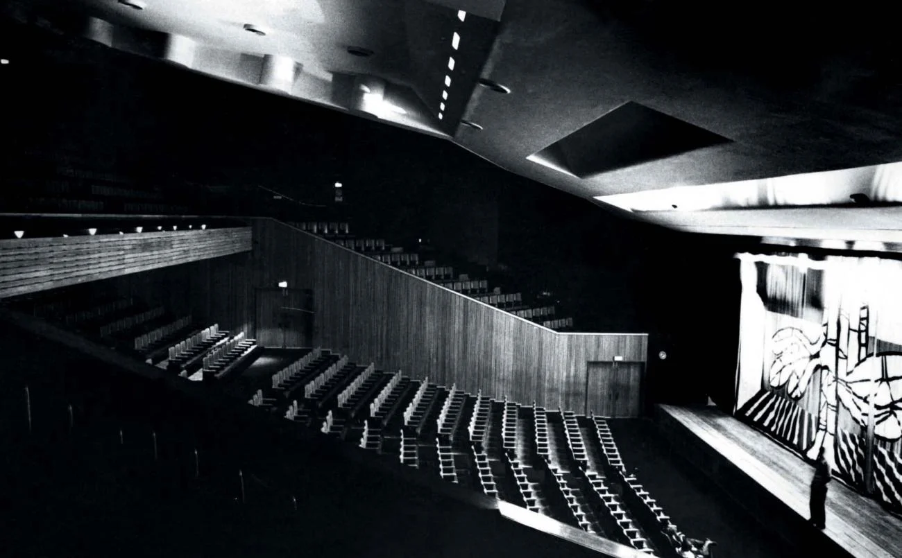 Black and white interior of Premabhai Hall by Balkrishna Doshi, showing a folded concrete ceiling over raked seating.