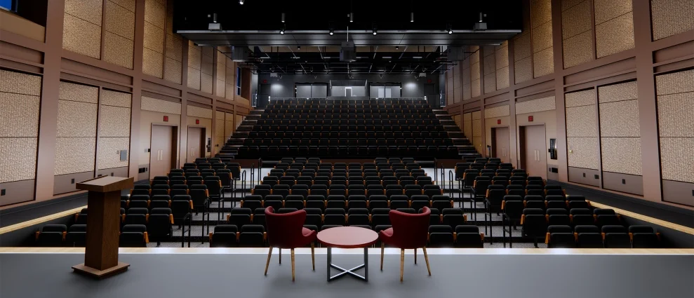 Interior auditorium with tiered dark seating, wooden acoustic wall panels, and a raised stage by Parallax Architecture and Planning.