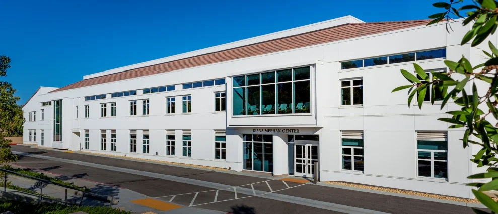Exterior view of the Diana Meehan Center by Parallax Architecture and Planning, featuring white stucco facade, clerestory windows, and deep-set glazing.