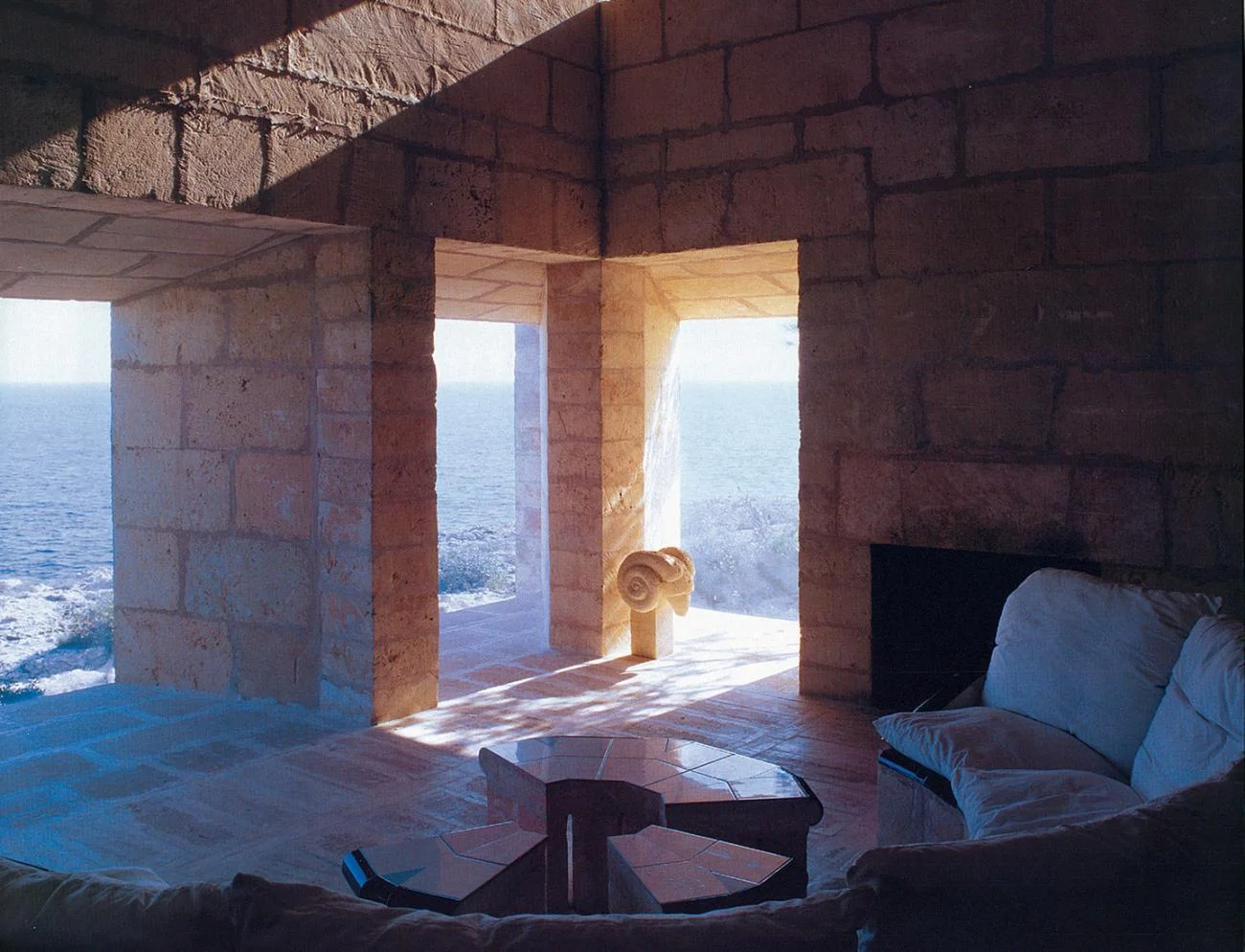 Interior of Can Lis by Jørn Utzon, showing thick sandstone piers framing views of the Mediterranean Sea.