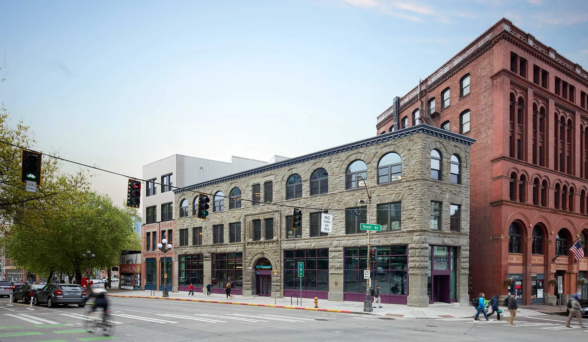 Exterior street view of The Metropole Building by BuildingWork featuring rusticated stone masonry and large storefront glazing.