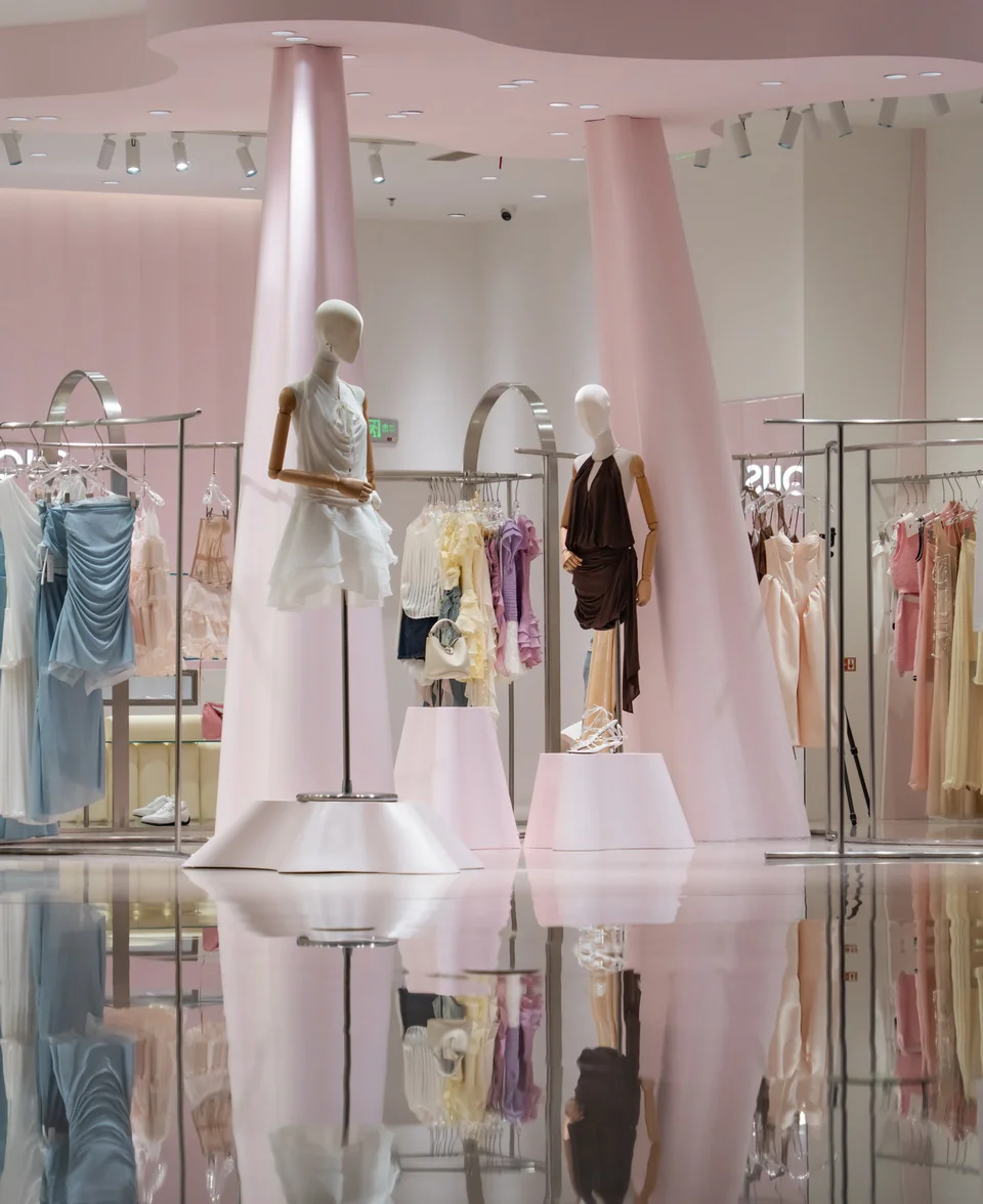 Interior of a boutique retail store designed by Airwall Architecture Office, featuring glossy reflective floors and monolithic pink tapered columns.