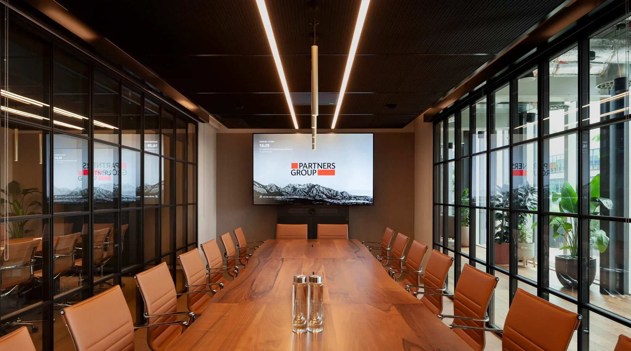 Executive conference room featuring a live-edge timber table, tan leather chairs, and dark metal-framed glass walls by PENSON.