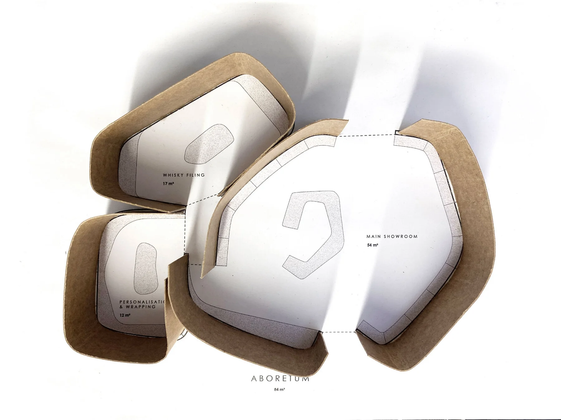 Physical layout model by Jamie Fobert Architects for The Macallan featuring curved cardboard perimeter bands defining zoned interior rooms with printed plans.