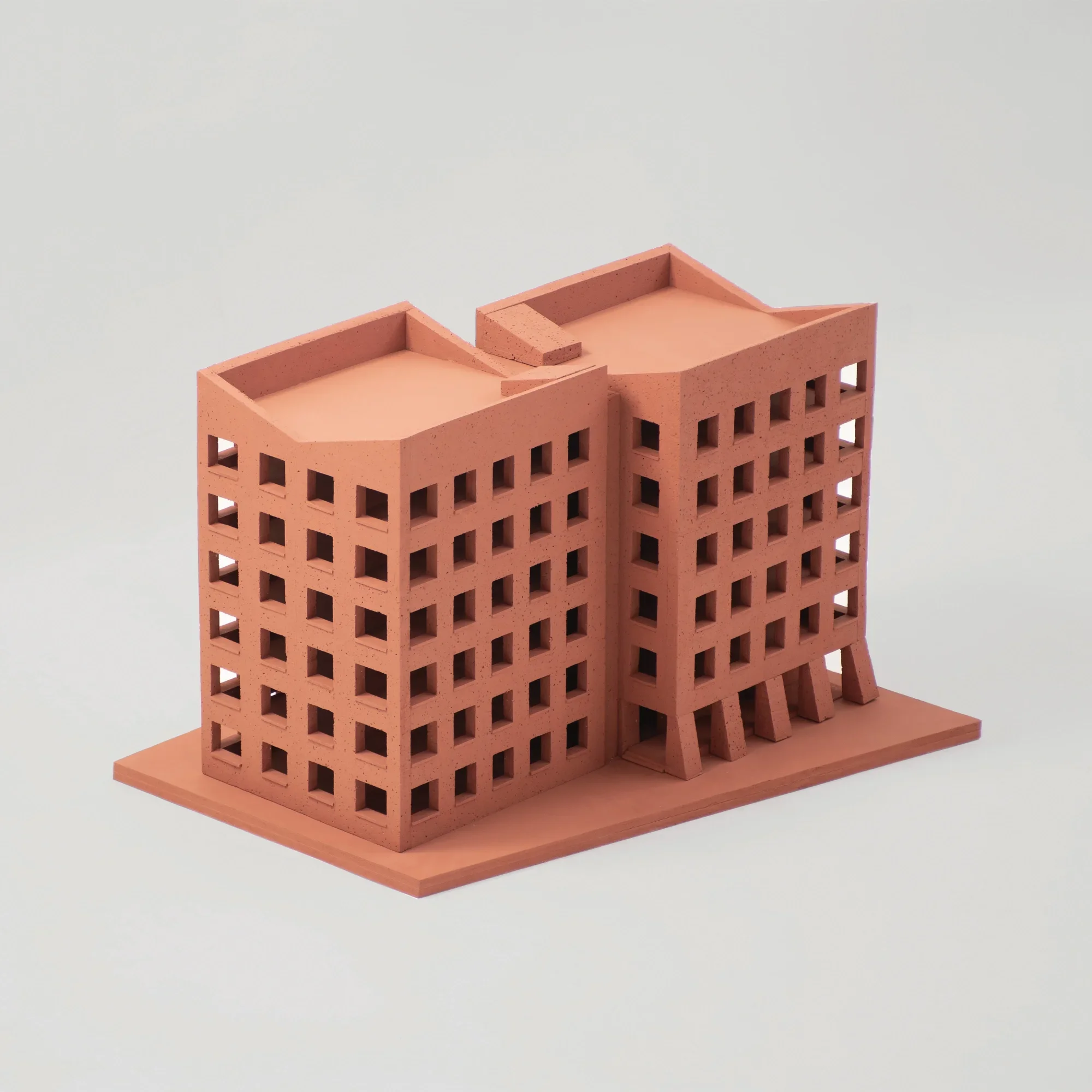 Physical architectural massing model of twin terracotta-colored buildings with punched windows by Al-Jawad Pike.